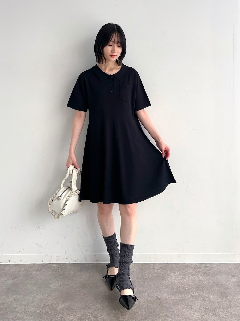 ブラック系のワンピース、ホワイト系のショルダーバッグ、ブラック系のパンプスを着用したレディースの夏コーディネートの2枚目の写真