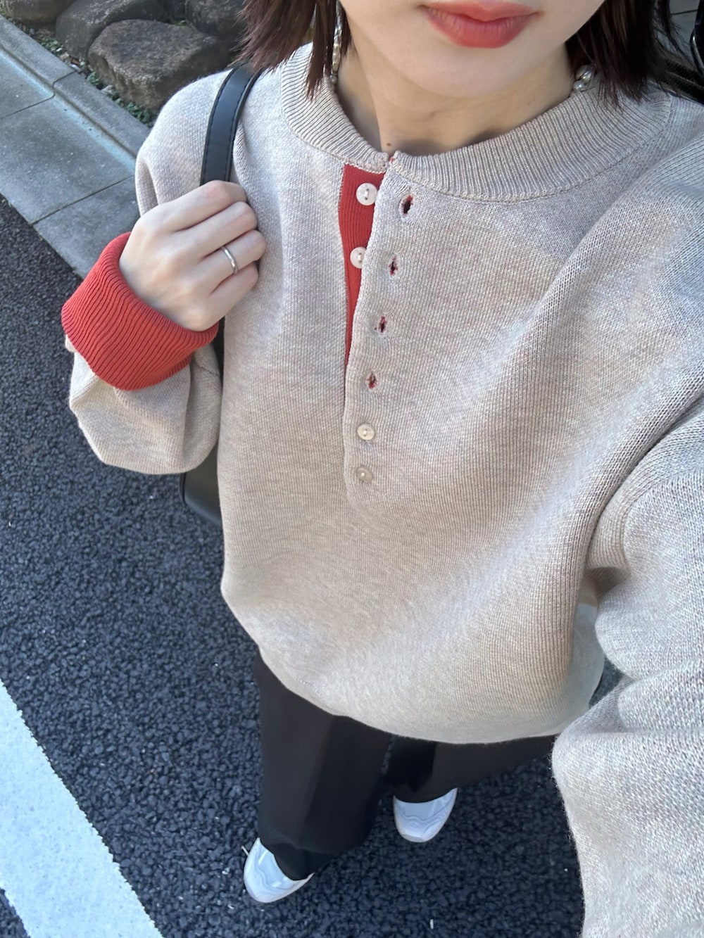 ベージュ系のニット/セーター、ブラック系のスラックス、ブラック系のハンドバッグを着用したレディースの秋コーディネートの4枚目の写真