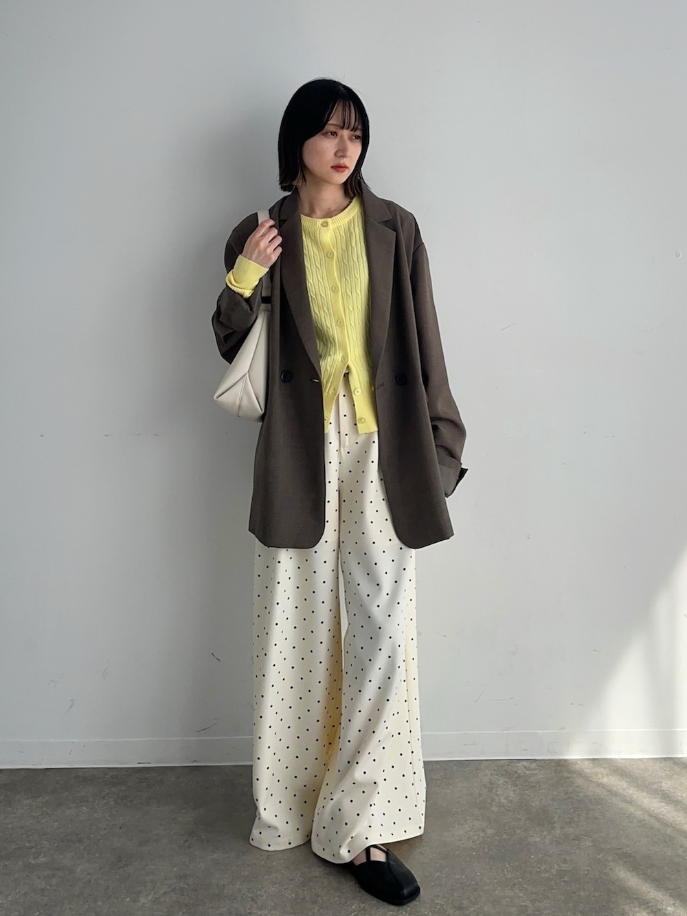 イエロー系のカーディガン/ボレロ、ベージュ系のテーラードジャケット、ベージュ系のスラックスを着用したレディースの春コーディネートの2枚目の写真