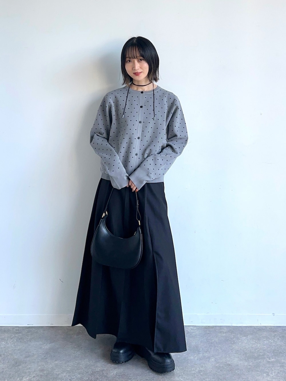 ブラック系のハンドバッグ、グレー系のカーディガン/ボレロ、ブラック系のスカートを着用したレディースの冬コーディネートの2枚目の写真