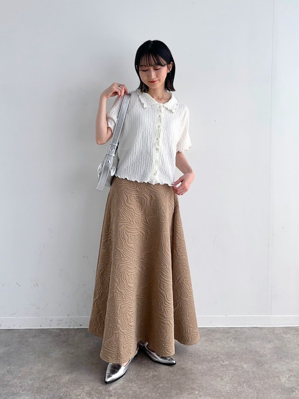 ホワイト系のシャツ/ブラウス、ベージュ系のスカート、シルバー系のショルダーバッグを着用したレディースの春コーディネートの2枚目の写真