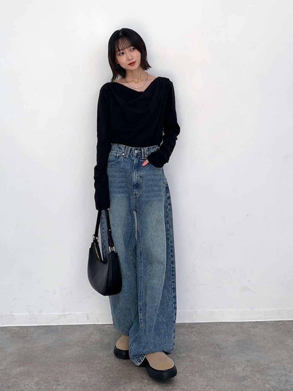 ブルー系のデニムパンツ、ブラック系のハンドバッグ、ブラック系のTシャツ/カットソーを着用したレディースの秋コーディネートの2枚目の写真