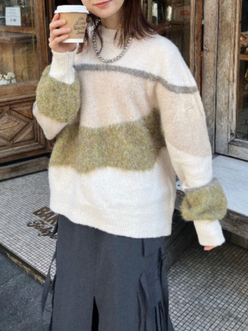 グレー系のスカート、ブラック系のブーツ、ホワイト系のニット/セーターを着用したレディースの冬コーディネートの2枚目の写真
