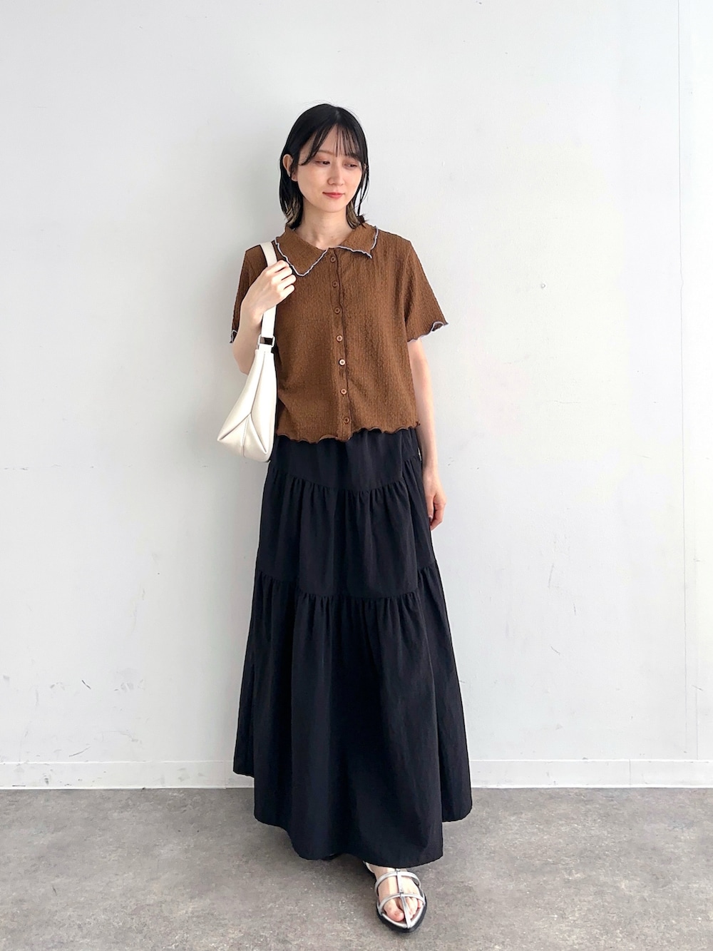 ブラウン系のシャツ/ブラウス、ブラック系のスカート、シルバー系のサンダルを着用したレディースの夏コーディネートの2枚目の写真