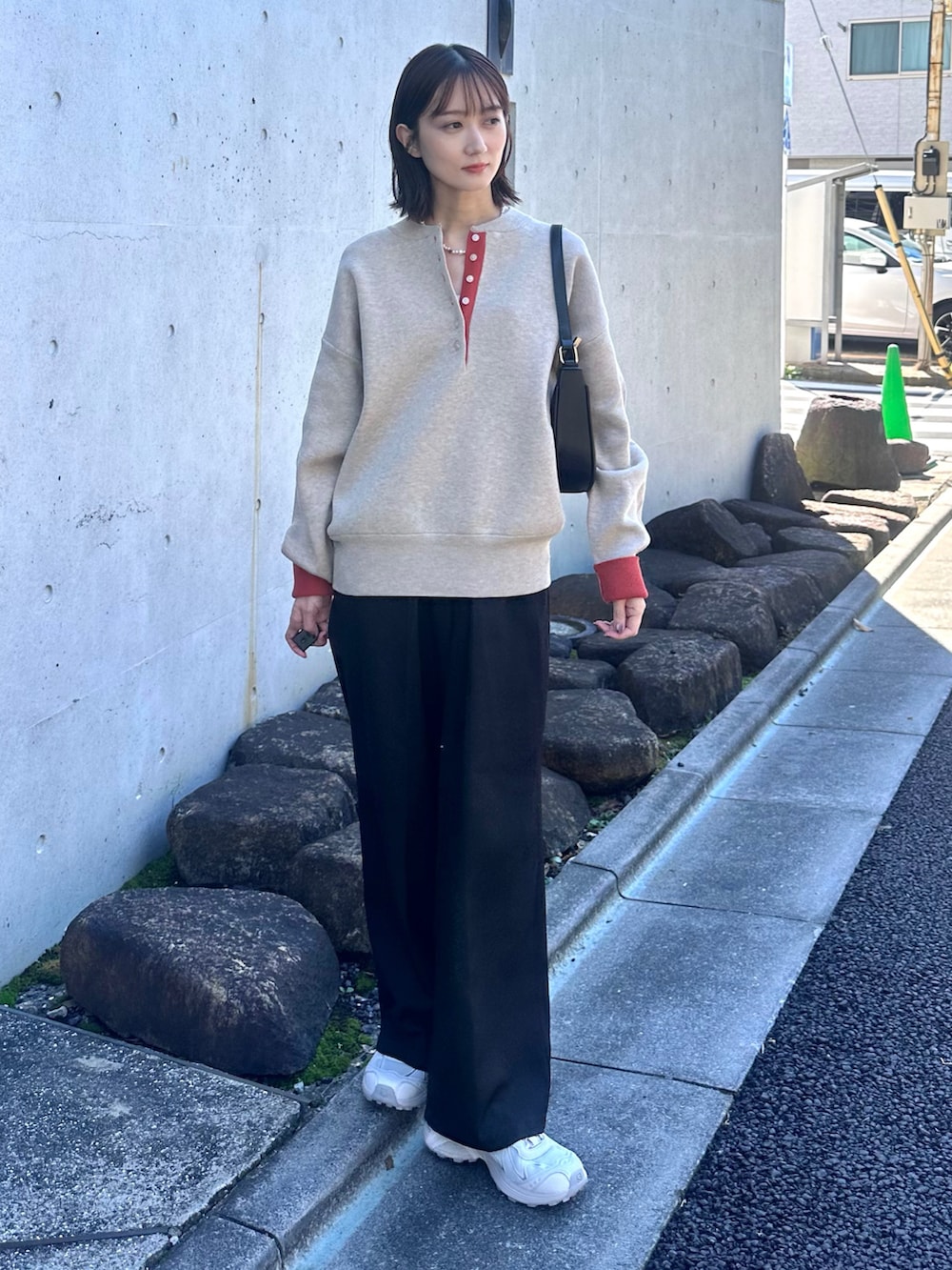 ベージュ系のニット/セーター、ブラック系のスラックス、ブラック系のハンドバッグを着用したレディースの秋コーディネートの2枚目の写真