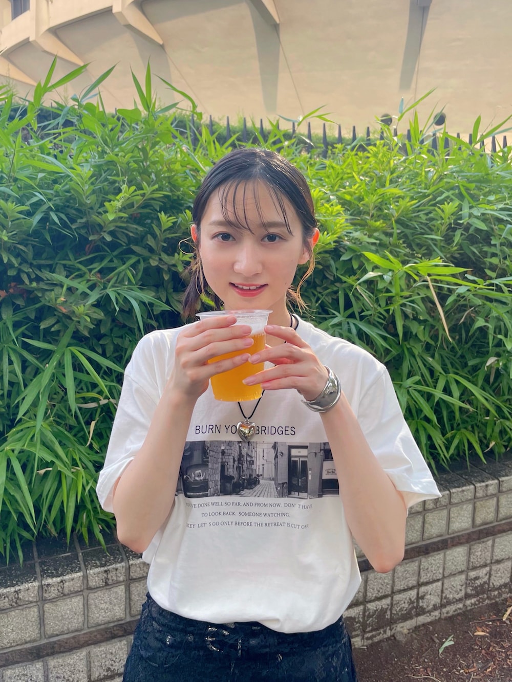 ブラック系のデニムパンツ、ブラック系のスニーカー、ホワイト系のTシャツ/カットソーを着用したレディースの夏コーディネートの2枚目の写真