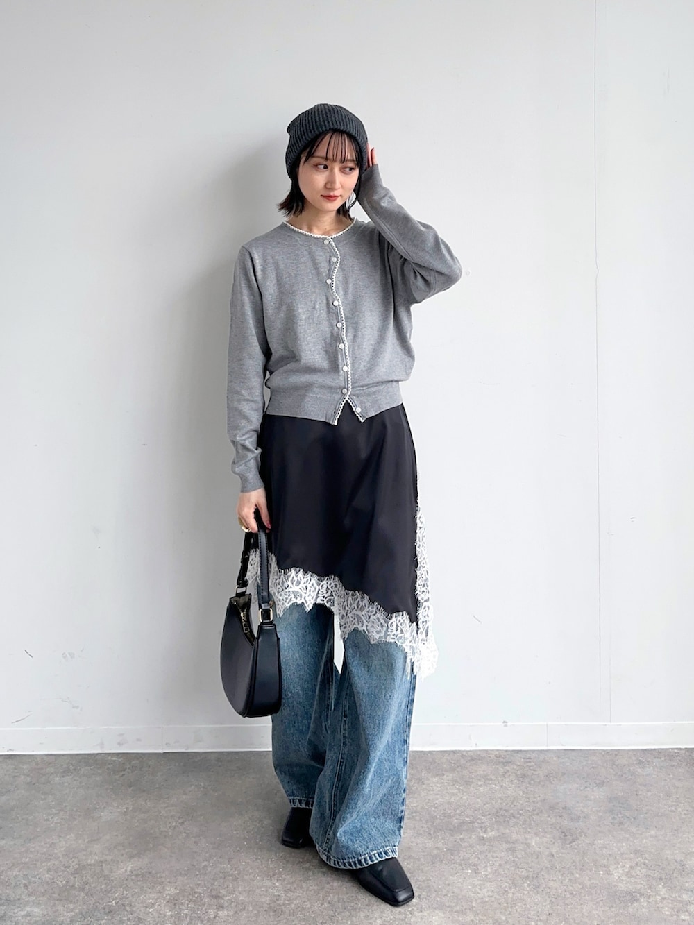 ブルー系のデニムパンツ、ブラック系のハンドバッグ、グレー系のカーディガン/ボレロを着用したレディースの春コーディネートの2枚目の写真