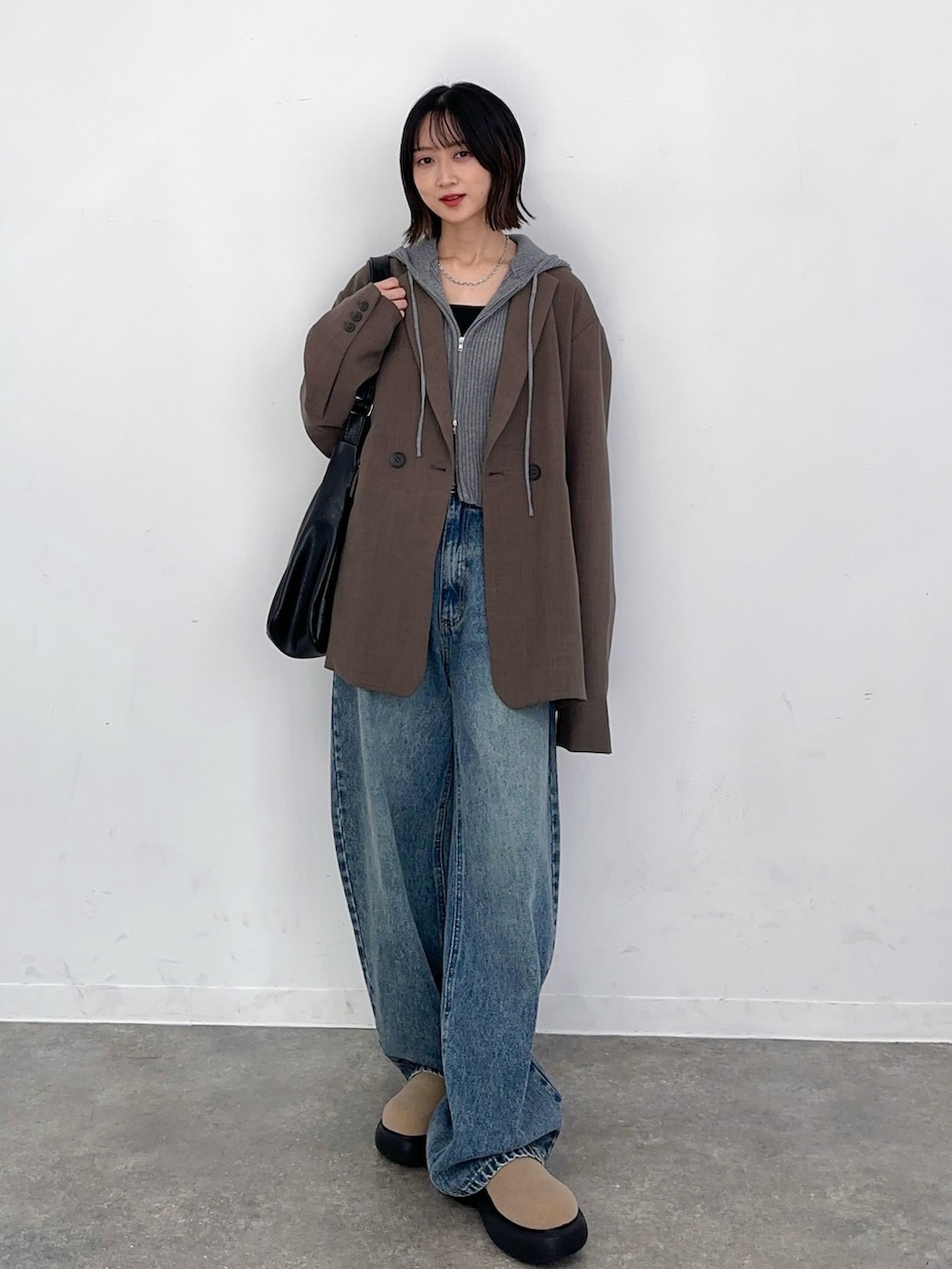 ブルー系のデニムパンツ、ブラック系のショルダーバッグ、グレー系のニット/セーターを着用したレディースの秋コーディネートの2枚目の写真