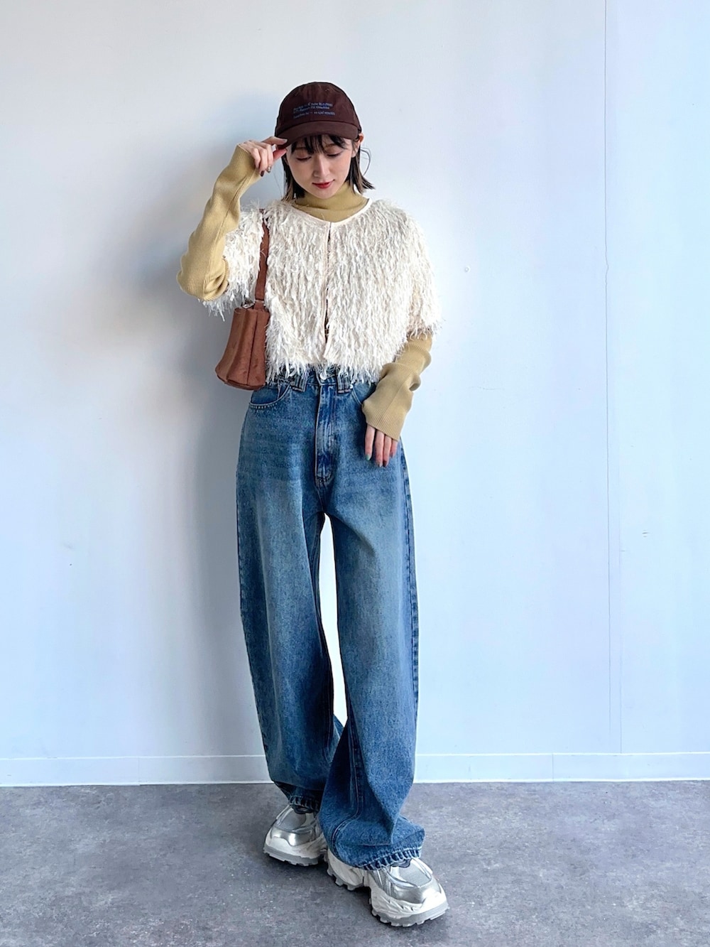 ベージュ系のカーディガン/ボレロ、イエロー系のニット/セーター、ブルー系のデニムパンツを着用したレディースの冬コーディネートの2枚目の写真