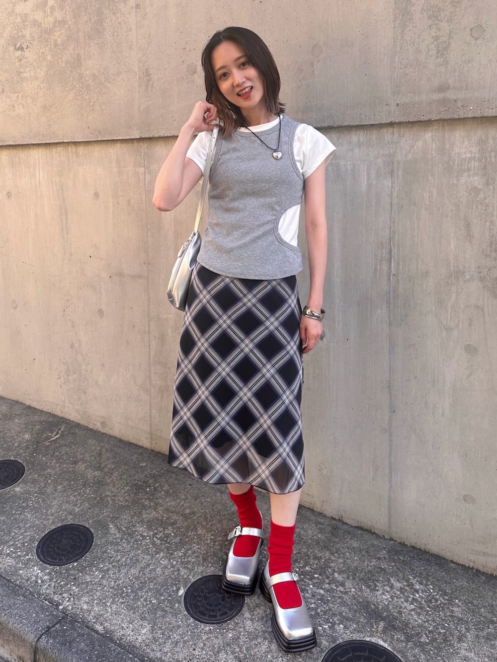 シルバー系のハンドバッグ、グレー系のTシャツ/カットソー、ブルー系のスカートを着用したレディースの夏コーディネートの3枚目の写真