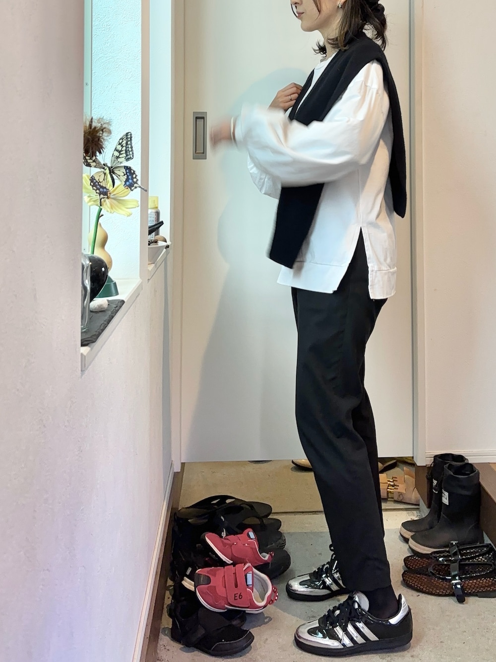 ブラック系のスニーカー、ホワイト系のトップス、ブラック系のベストを着用したレディースの秋コーディネートの2枚目の写真
