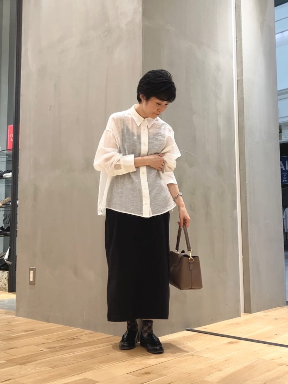 ホワイト系のシャツ/ブラウス、ブラック系のスカート、ブラウン系のショルダーバッグを着用したレディースの夏コーディネートの2枚目の写真