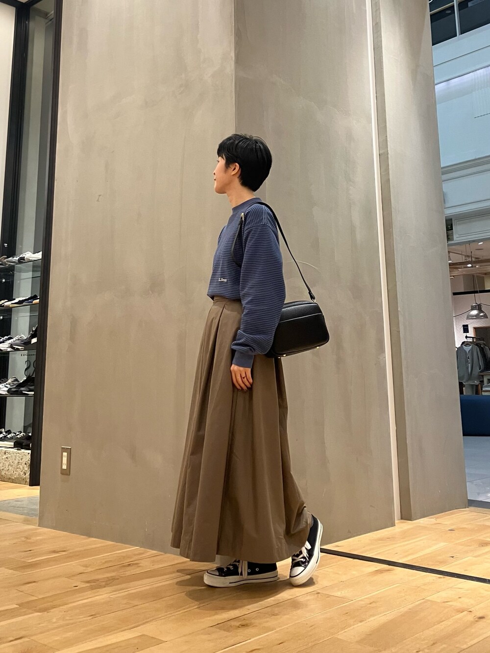 ブルー系のTシャツ/カットソー、ブラウン系のブルゾン、ブラウン系のスカートを着用したレディースの秋コーディネートの7枚目の写真
