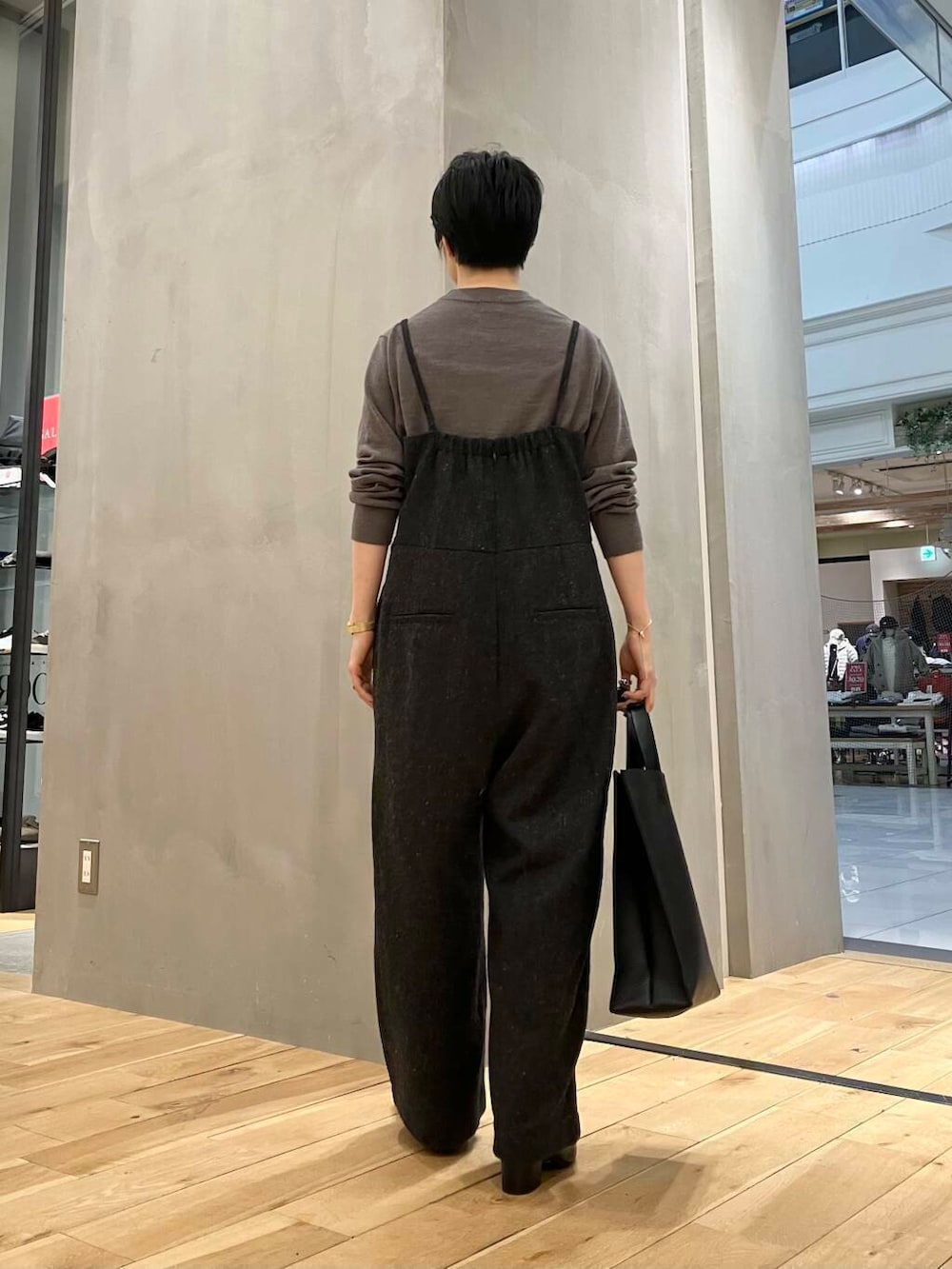 ブラウン系のニット/セーター、ブラウン系のステンカラーコート、グレー系のサロペット/オーバーオールを着用したレディースの冬コーディネートの6枚目の写真