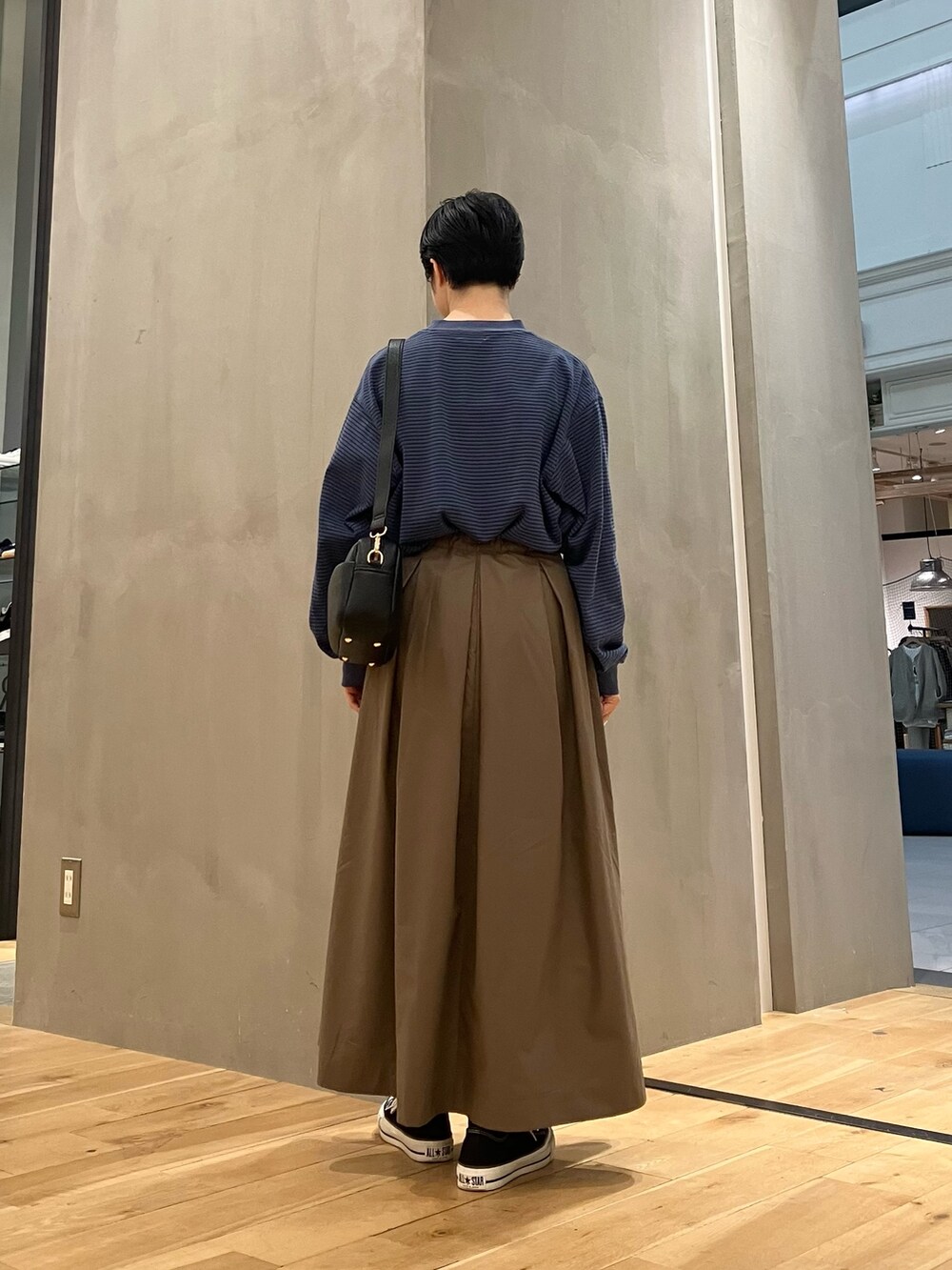ブルー系のTシャツ/カットソー、ブラウン系のブルゾン、ブラウン系のスカートを着用したレディースの秋コーディネートの6枚目の写真