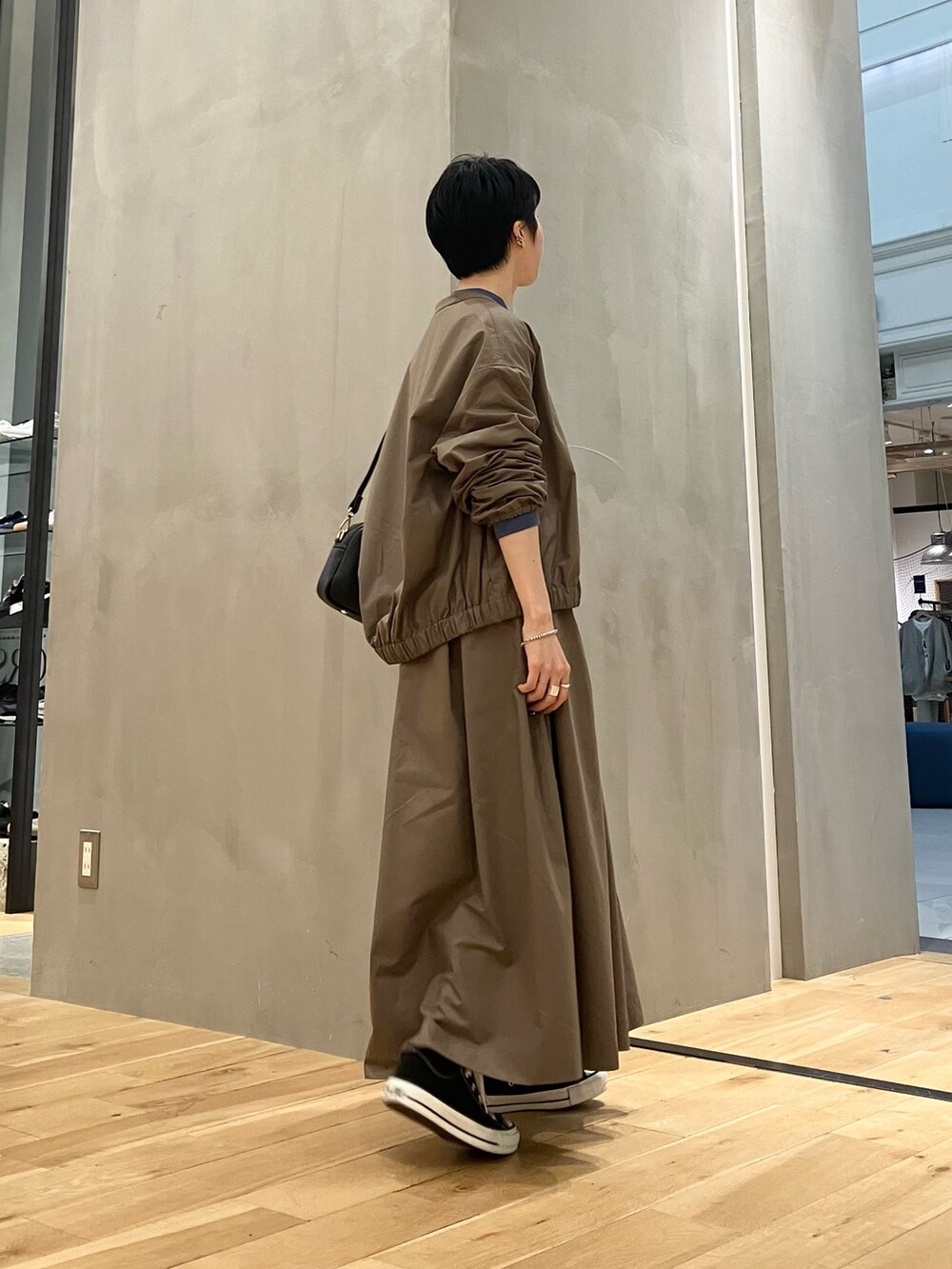 ブルー系のTシャツ/カットソー、ブラウン系のブルゾン、ブラウン系のスカートを着用したレディースの秋コーディネートの2枚目の写真
