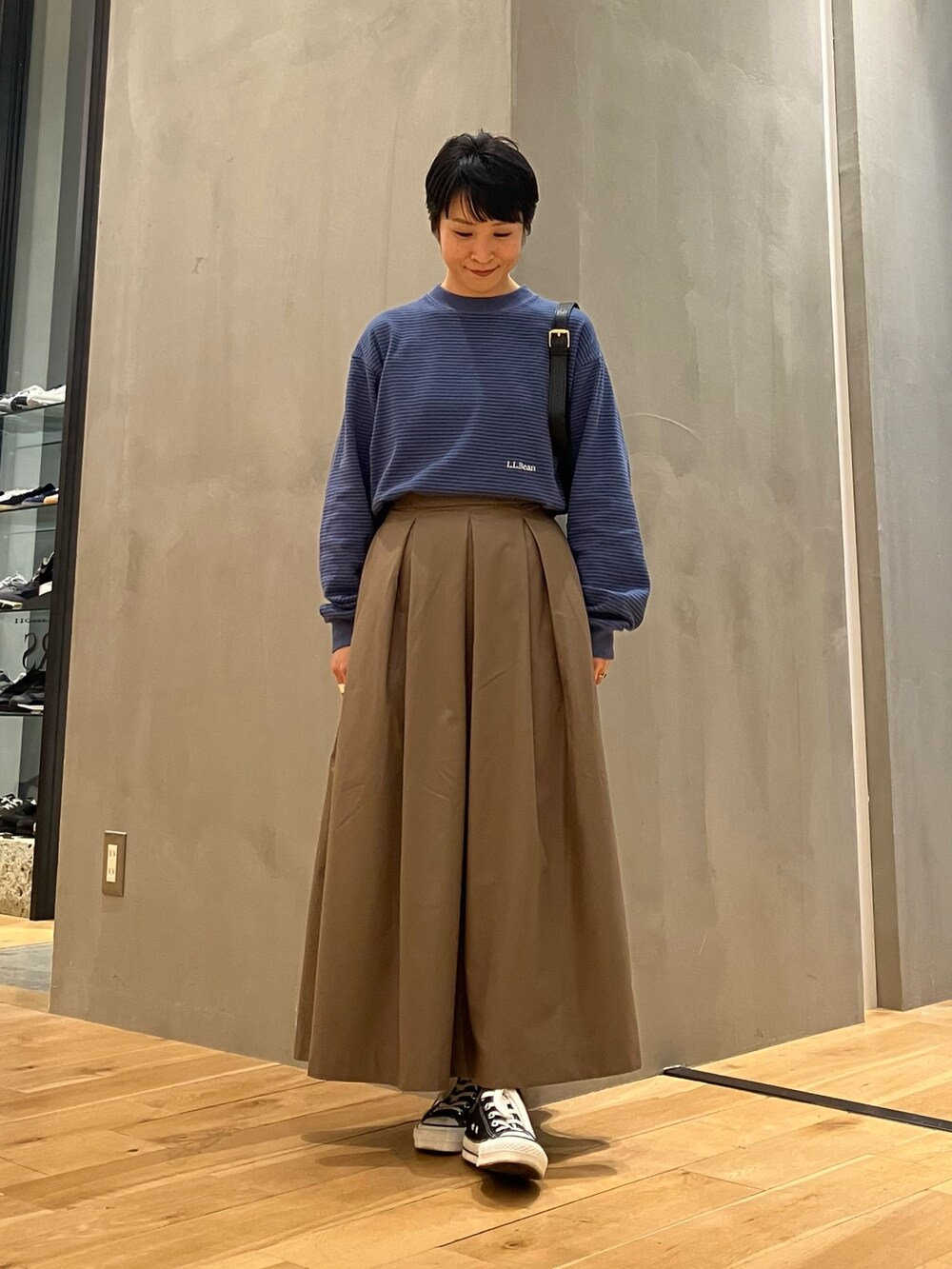 ブルー系のTシャツ/カットソー、ブラウン系のブルゾン、ブラウン系のスカートを着用したレディースの秋コーディネートの4枚目の写真