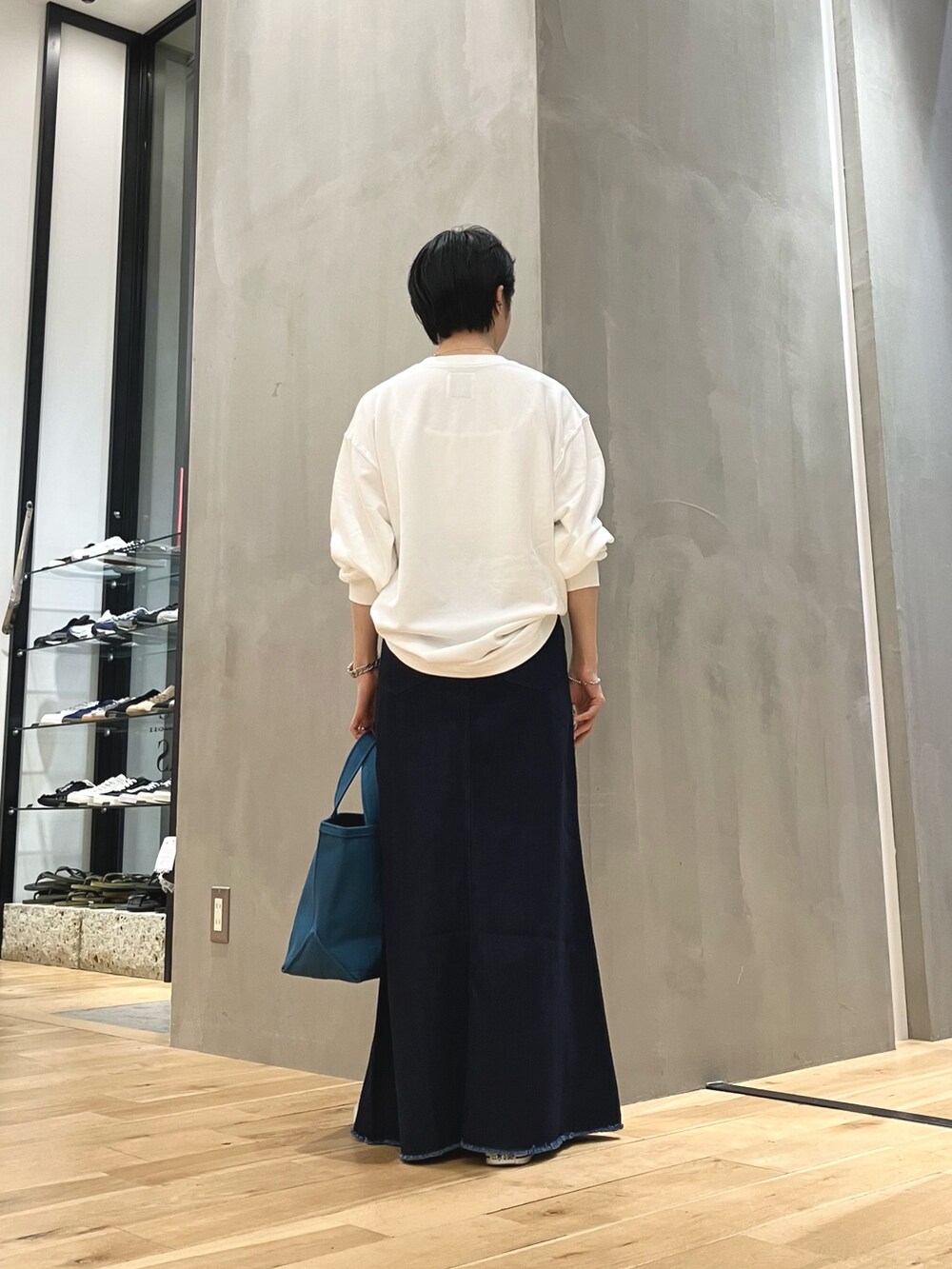 ブルー系のスカート、ブルー系のトートバッグ、ブラック系のスニーカーを着用したレディースの夏コーディネートの4枚目の写真