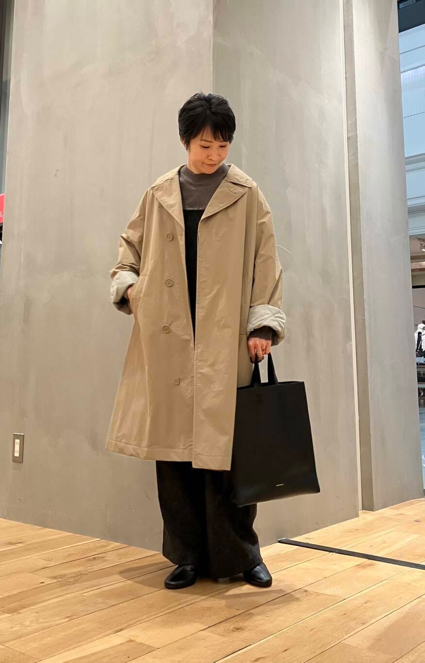 ブラウン系のニット/セーター、ブラウン系のステンカラーコート、グレー系のサロペット/オーバーオールを着用したレディースの冬コーディネートの2枚目の写真