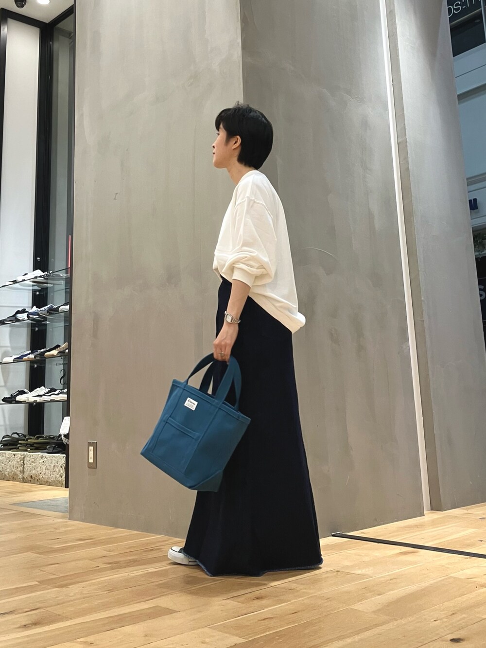 ブルー系のスカート、ブルー系のトートバッグ、ブラック系のスニーカーを着用したレディースの夏コーディネートの3枚目の写真