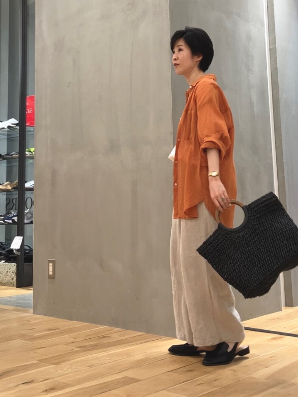 ベージュ系のその他パンツ、オレンジ系のシャツ/ブラウス、ブラック系のローファーを着用したレディースの夏コーディネートの3枚目の写真