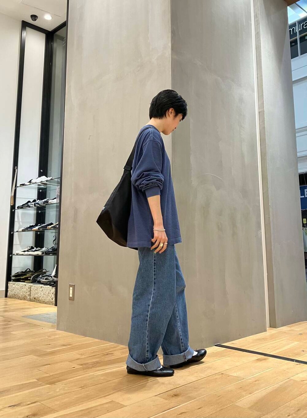 ブラック系のバレエシューズ、ブルー系のデニムパンツ、ブラック系のショルダーバッグを着用したレディースの夏コーディネートの3枚目の写真