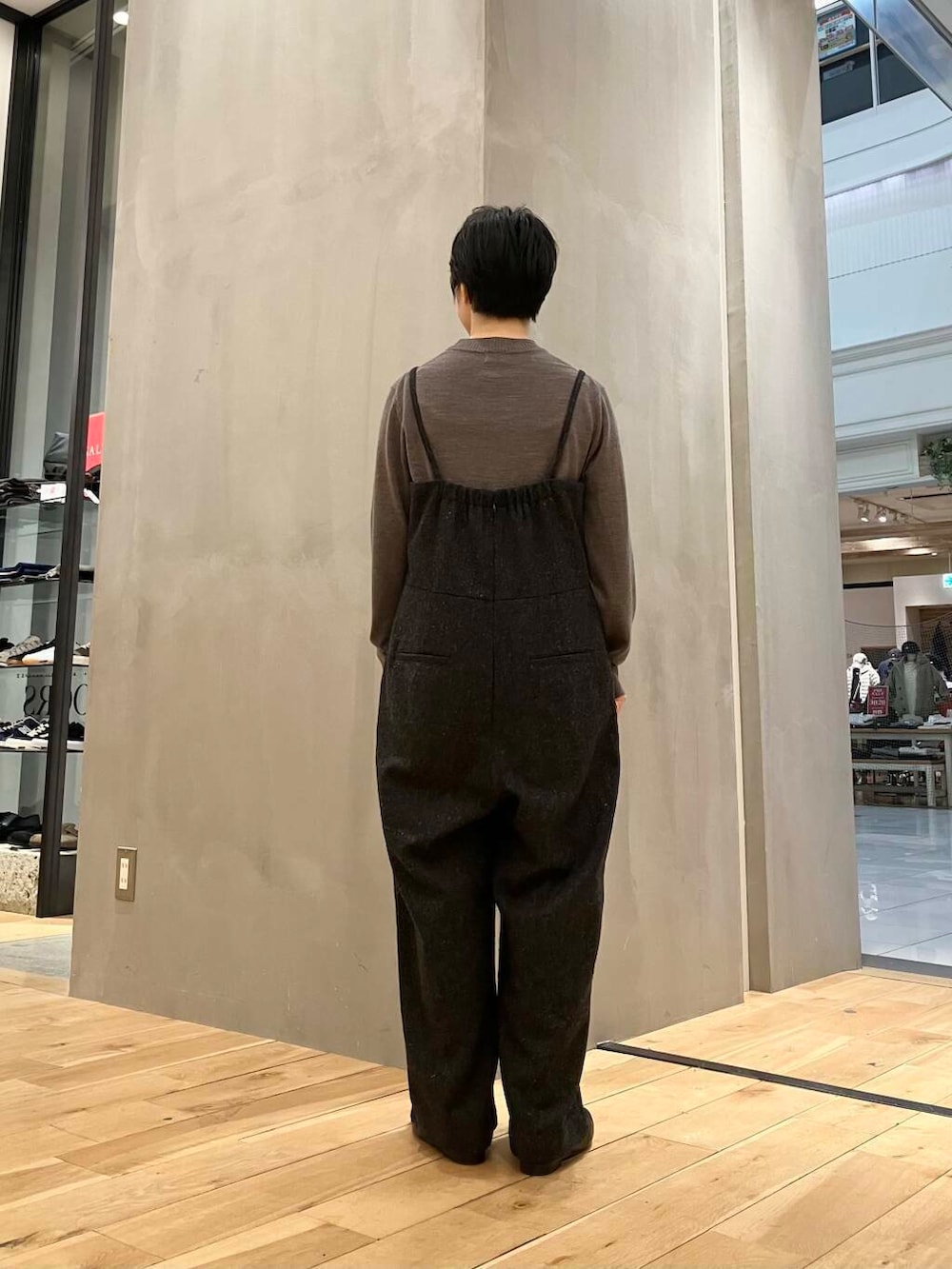 ブラウン系のニット/セーター、ブラウン系のステンカラーコート、グレー系のサロペット/オーバーオールを着用したレディースの冬コーディネートの7枚目の写真