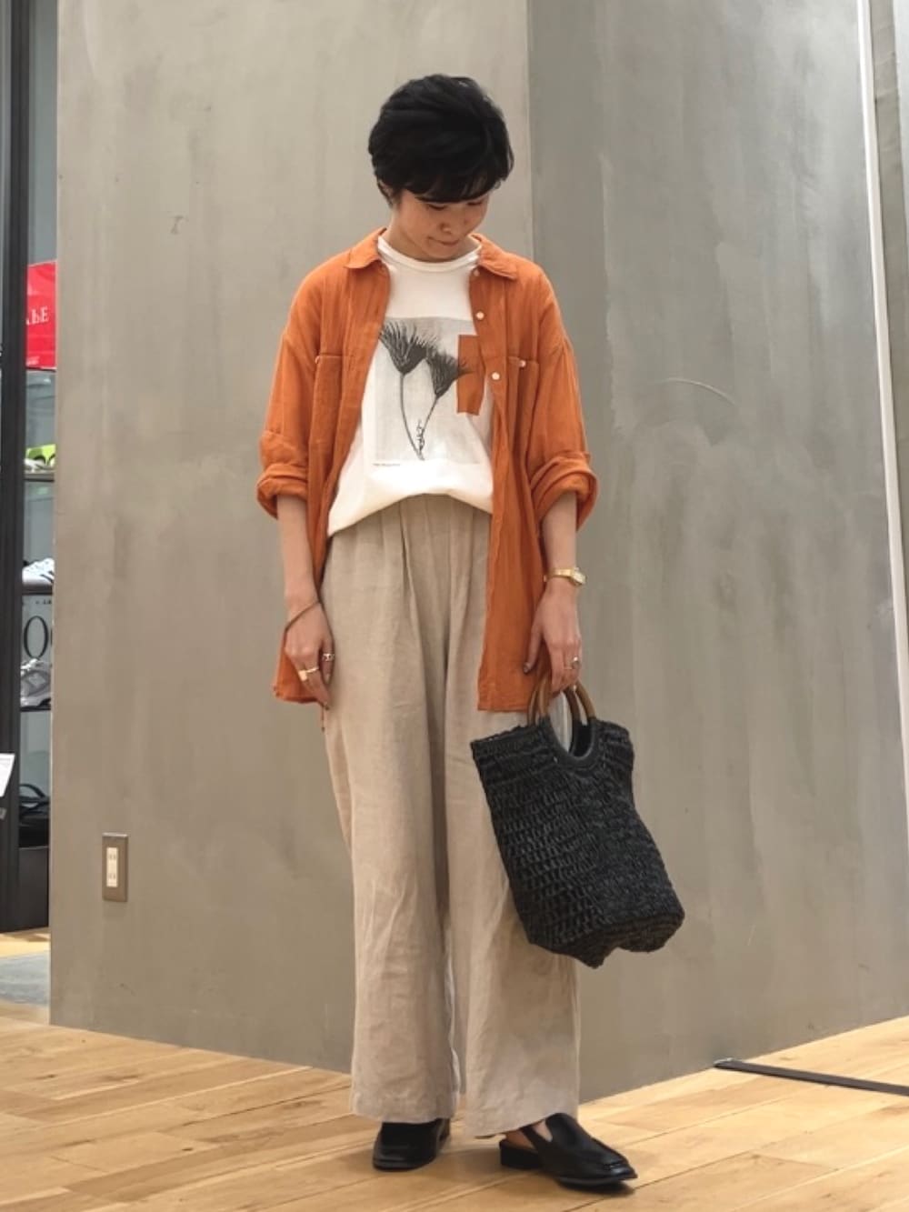 ベージュ系のその他パンツ、オレンジ系のシャツ/ブラウス、ブラック系のローファーを着用したレディースの夏コーディネートの2枚目の写真
