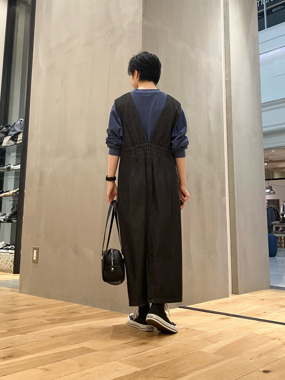 ブラック系のワンピース、ブラック系のボストンバッグ、ブラック系のスニーカーを着用したレディースの秋コーディネートの3枚目の写真