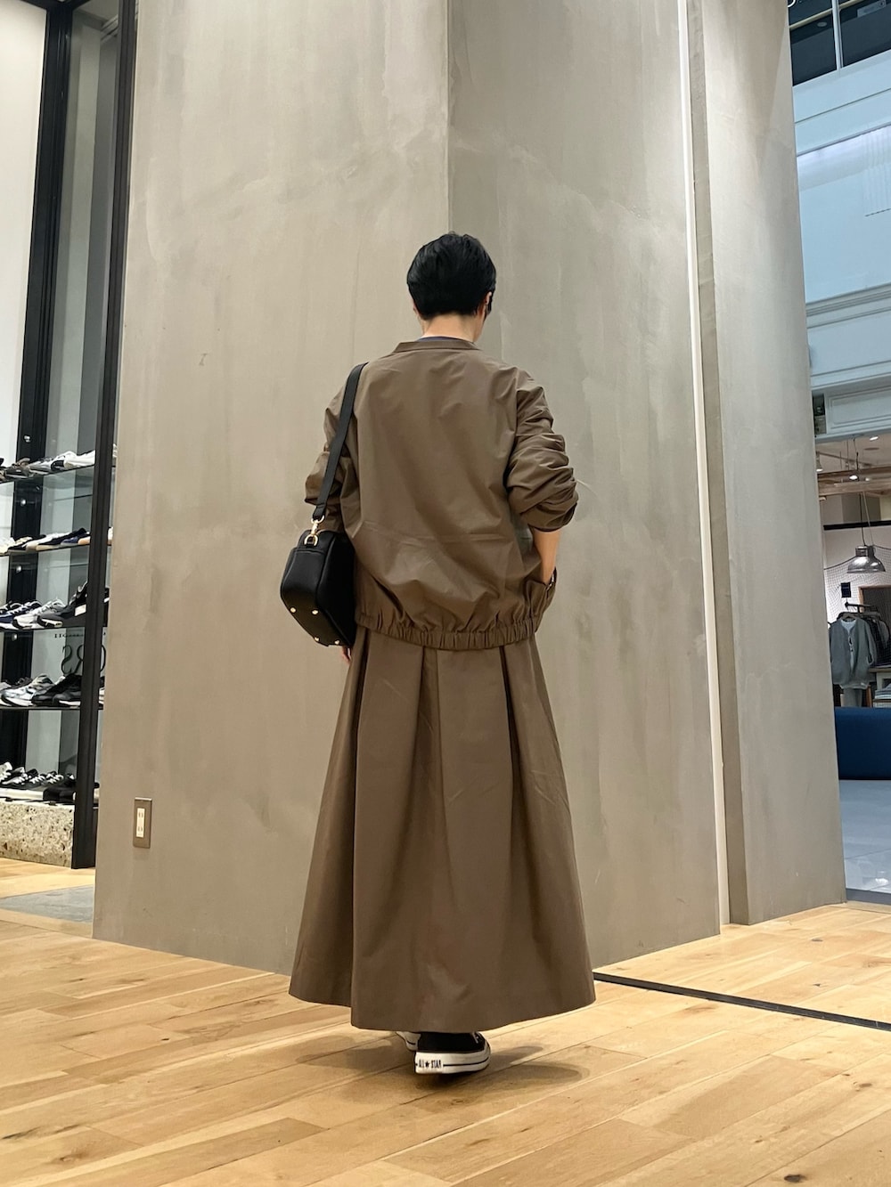 ブルー系のTシャツ/カットソー、ブラウン系のブルゾン、ブラウン系のスカートを着用したレディースの秋コーディネートの3枚目の写真