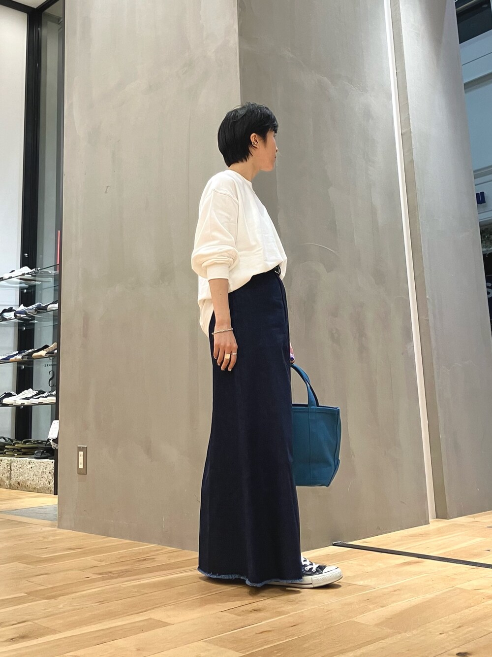 ブルー系のスカート、ブルー系のトートバッグ、ブラック系のスニーカーを着用したレディースの夏コーディネートの5枚目の写真