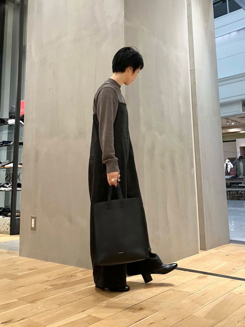 ブラウン系のニット/セーター、ブラウン系のステンカラーコート、グレー系のサロペット/オーバーオールを着用したレディースの冬コーディネートの5枚目の写真