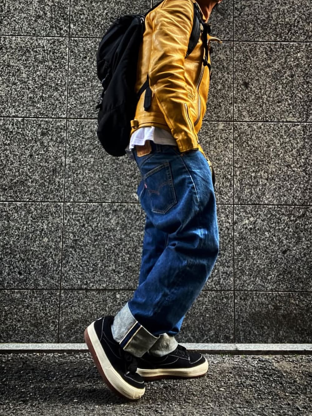 イエロー系のライダースジャケット、ホワイト系のTシャツ/カットソー、ブルー系のデニムパンツを着用したメンズの春コーディネートの2枚目の写真