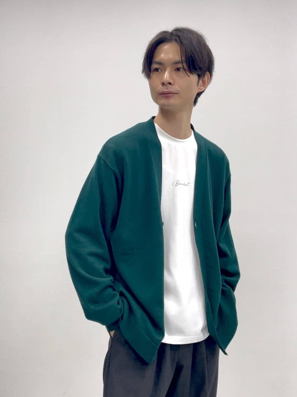 グリーン系のカーディガン/ボレロ、グレー系のスラックスを着用したメンズの冬コーディネートの2枚目の写真