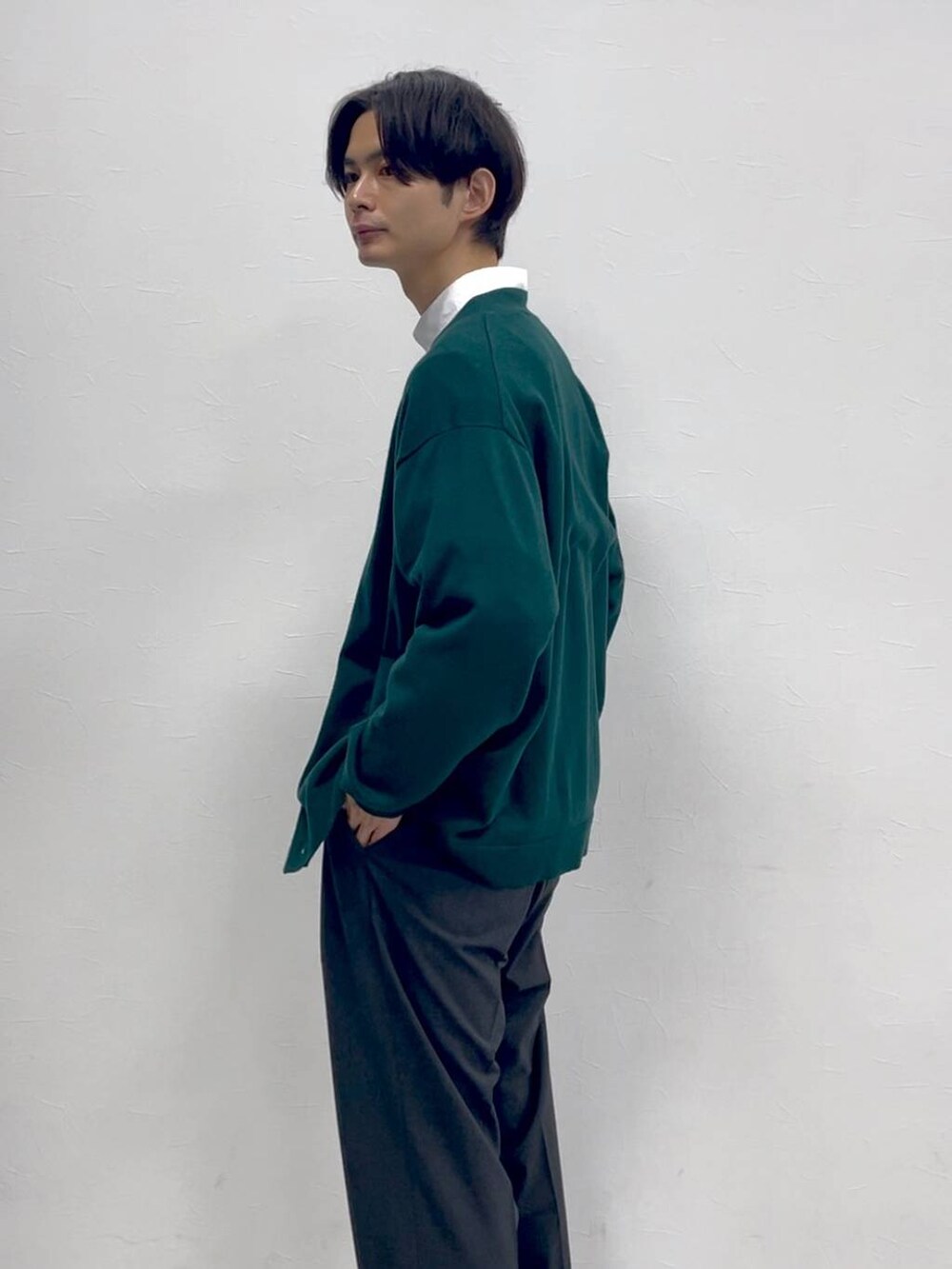 グレー系のスラックス、グリーン系のカーディガン/ボレロ、ホワイト系のシャツ/ブラウスを着用したメンズの冬コーディネートの2枚目の写真