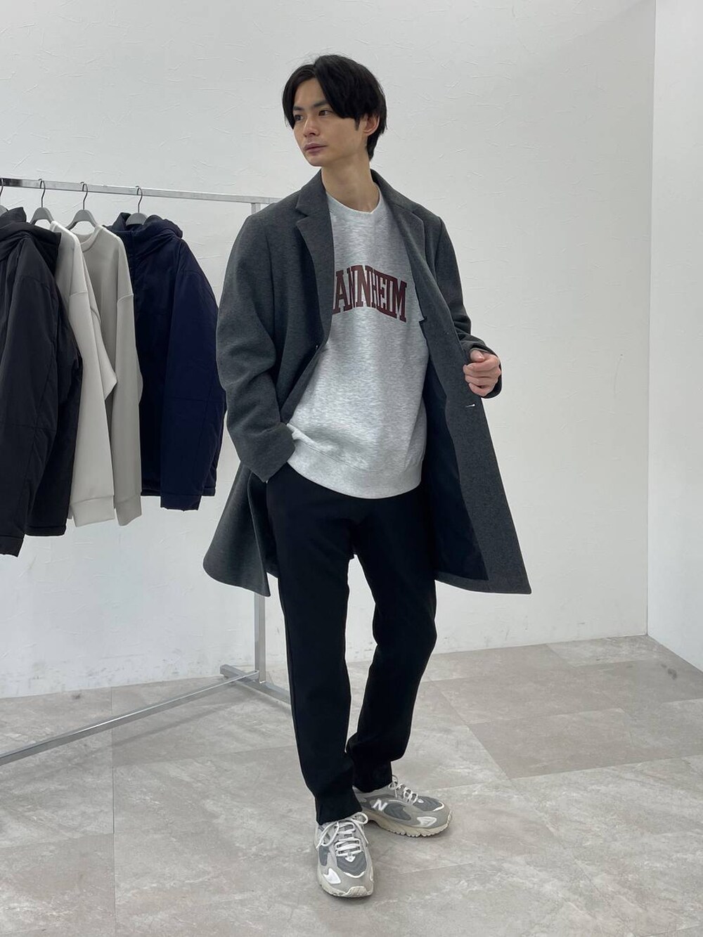 グレー系のチェスターコート、グレー系のスウェット、ブラック系のその他パンツを着用したメンズの冬コーディネートの2枚目の写真