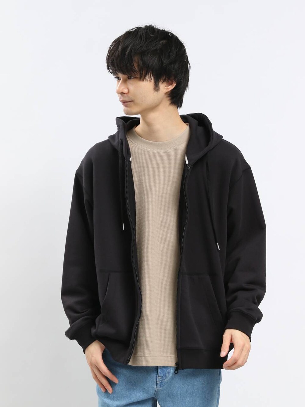 ブルー系のデニムパンツ、ブラック系のパーカー、ベージュ系のTシャツ/カットソーを着用したメンズの春コーディネートの2枚目の写真