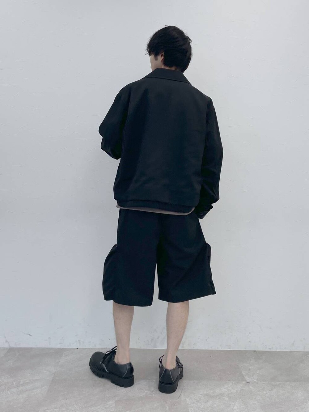 ブラック系のブルゾン、ブラウン系のTシャツ/カットソー、ブラック系のカーゴパンツを着用したメンズの冬コーディネートの2枚目の写真