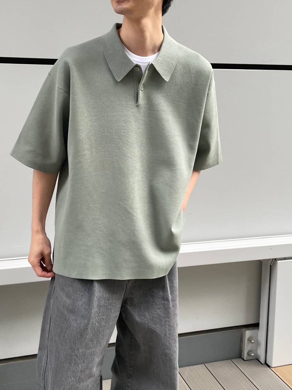 グリーン系のポロシャツ、グレー系のデニムパンツを着用したメンズの春コーディネートの5枚目の写真