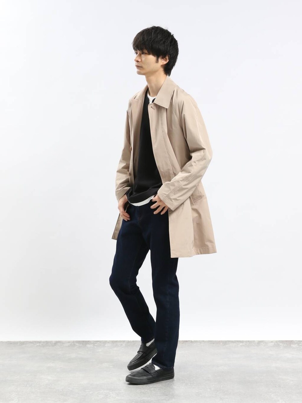 ブルー系のデニムパンツ、ベージュ系のステンカラーコート、ブラック系のTシャツ/カットソーを着用したメンズの冬コーディネートの2枚目の写真