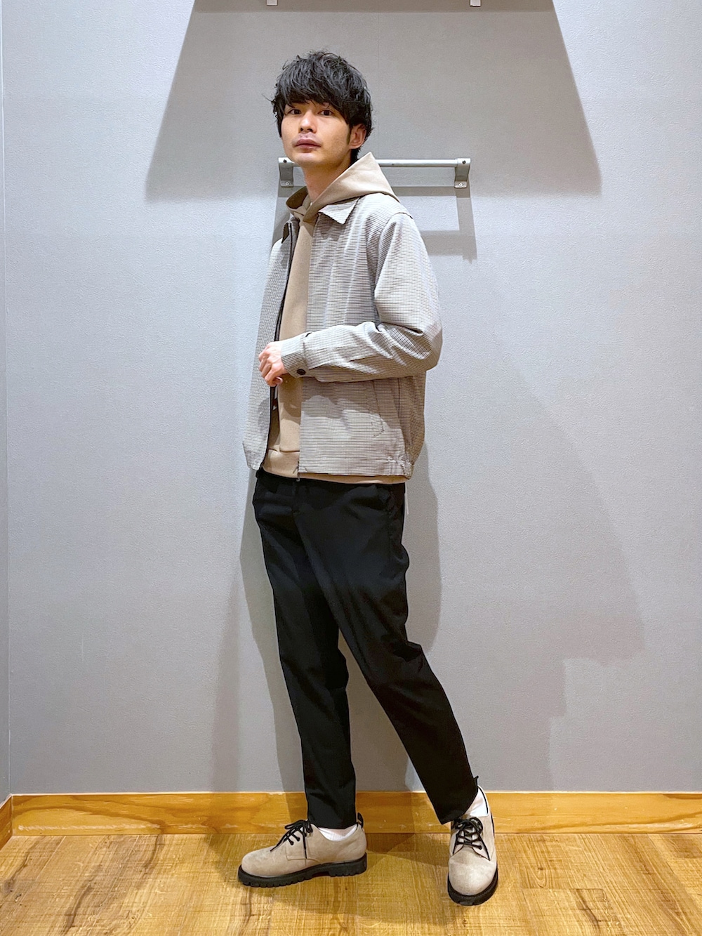 ブラウン系のブルゾン、ベージュ系のパーカー、ブラック系のスラックスを着用したメンズの春コーディネートの2枚目の写真