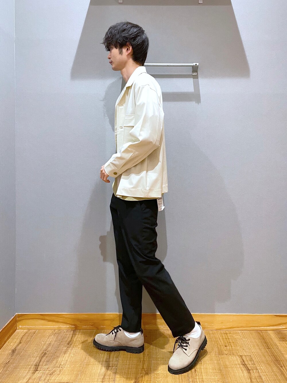 ブラック系のスラックス、ベージュ系のドレスシューズ、ホワイト系のテーラードジャケットを着用したメンズの春コーディネートの2枚目の写真