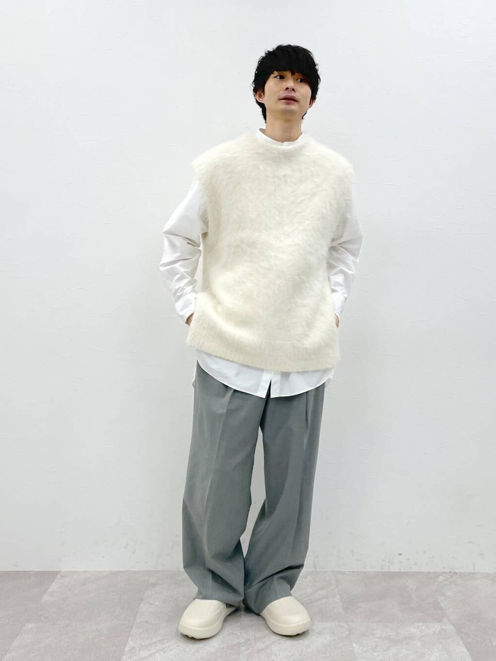 ホワイト系のシャツ/ブラウス、ホワイト系のニット/セーター、グレー系のスラックスを着用したメンズの冬コーディネートの6枚目の写真