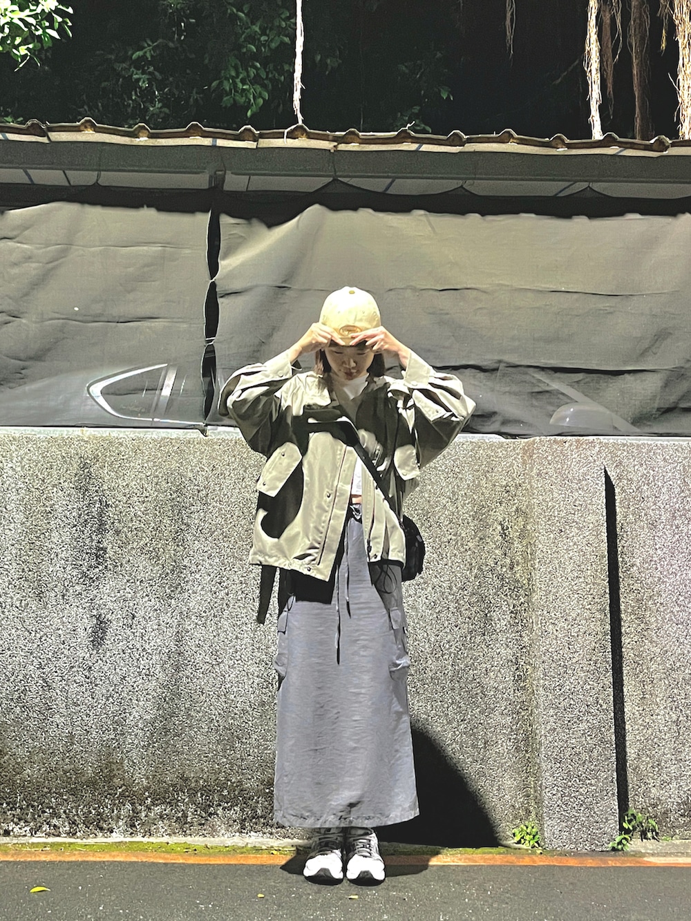 グリーン系のマウンテンパーカー、ホワイト系のキャップを着用したレディースの春コーディネートの2枚目の写真