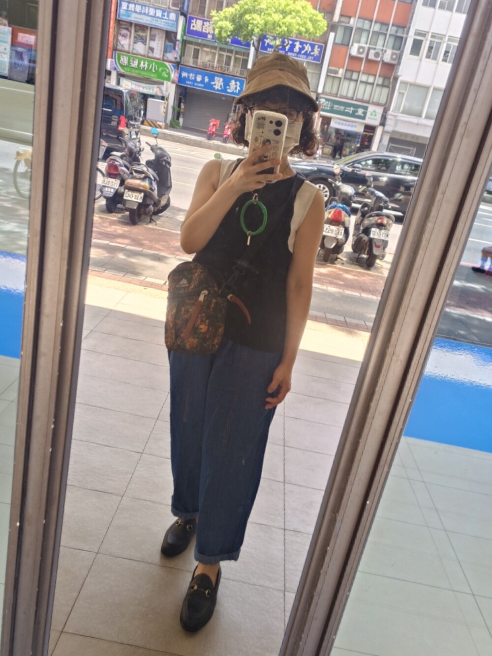 ブルー系のデニムパンツ、ブラック系のローファー、ブラウン系のショルダーバッグを着用したレディースの夏コーディネートの4枚目の写真