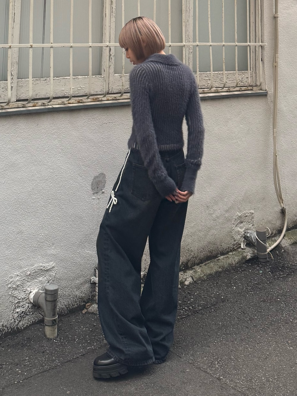 ブルー系のニット/セーター、ブルー系のデニムパンツ、ブラック系のブーツを着用したレディースの夏コーディネートの3枚目の写真