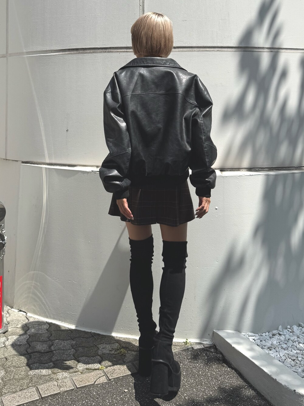 ブラック系のブルゾン、ブラック系のニット/セーター、ブラウン系のスカートを着用したレディースの秋コーディネートの2枚目の写真