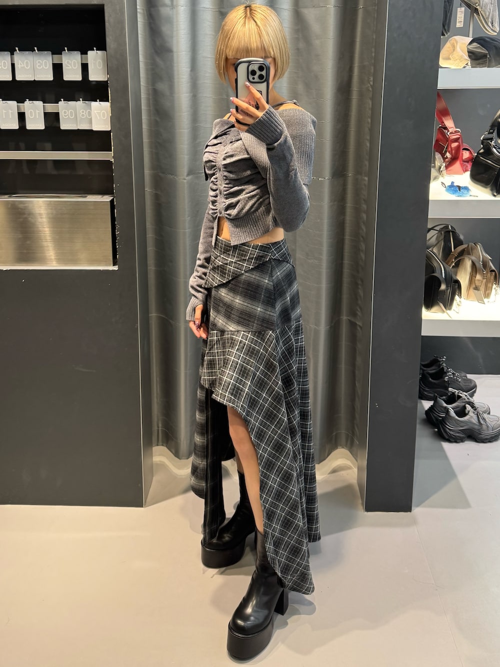 グレー系のニット/セーター、ブラック系のスカート、ブラック系のブーツを着用したレディースの秋コーディネートの2枚目の写真