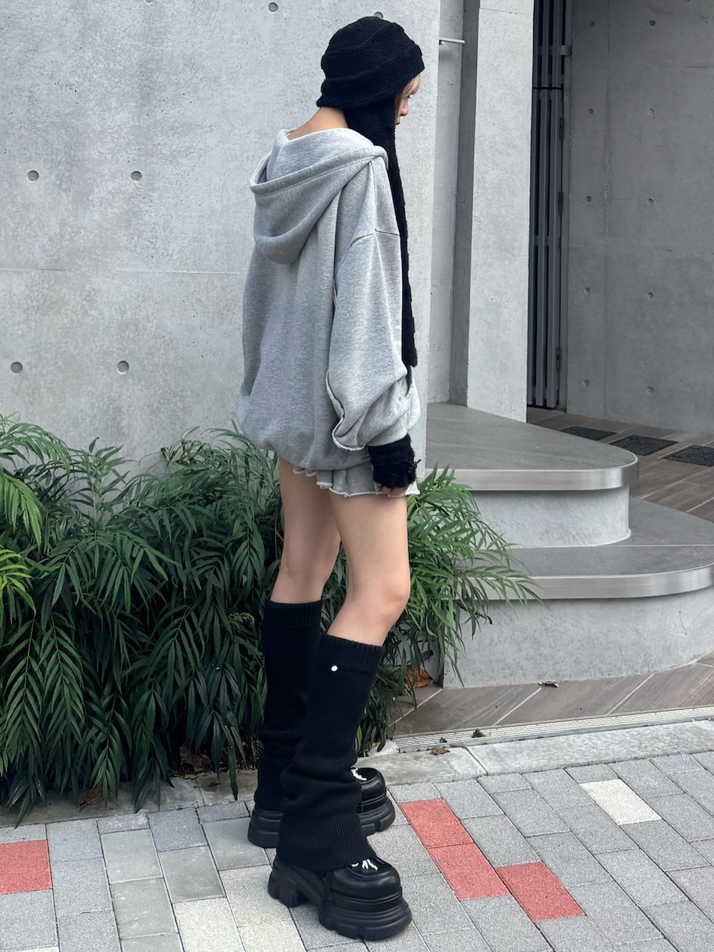 グレー系のパーカー、グレー系のスカート、ブラック系のローファーを着用したレディースの夏コーディネートの2枚目の写真