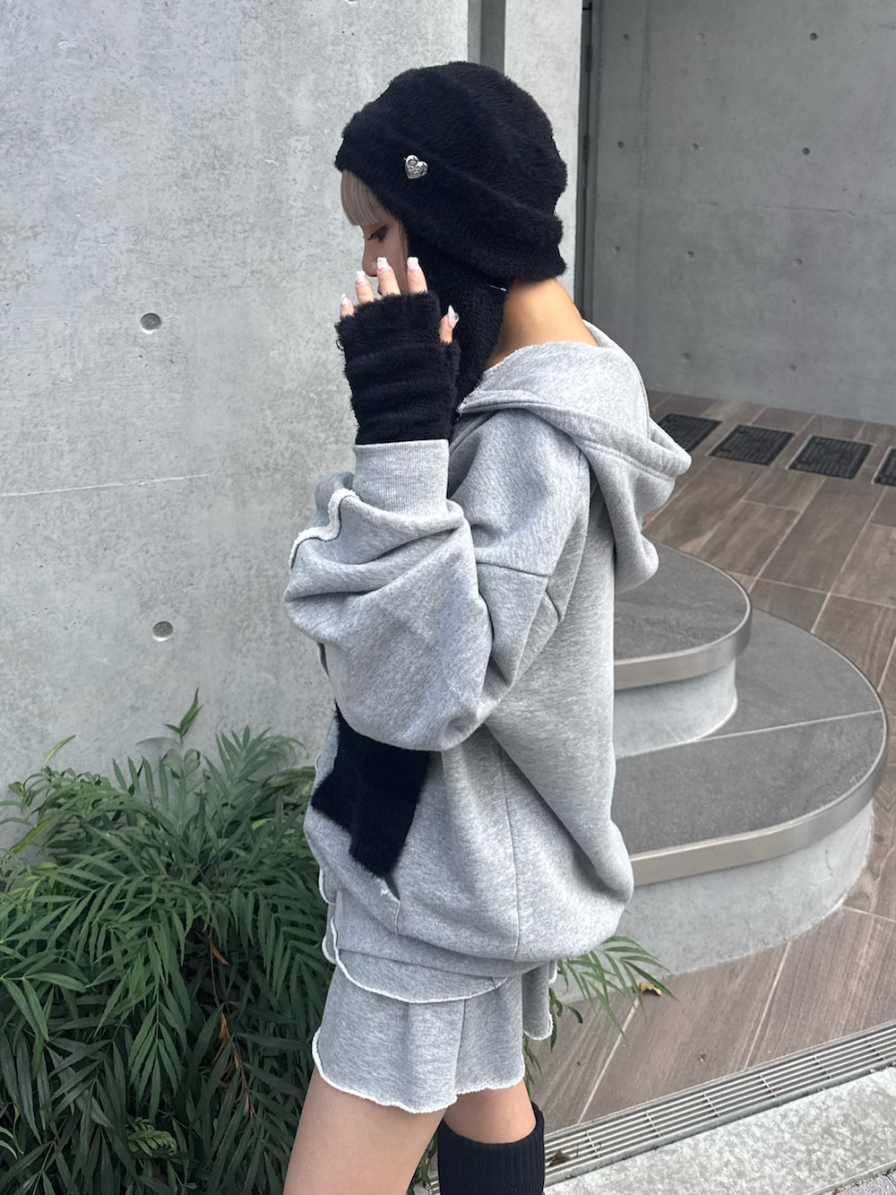 グレー系のパーカー、グレー系のスカート、ブラック系のローファーを着用したレディースの夏コーディネートの4枚目の写真